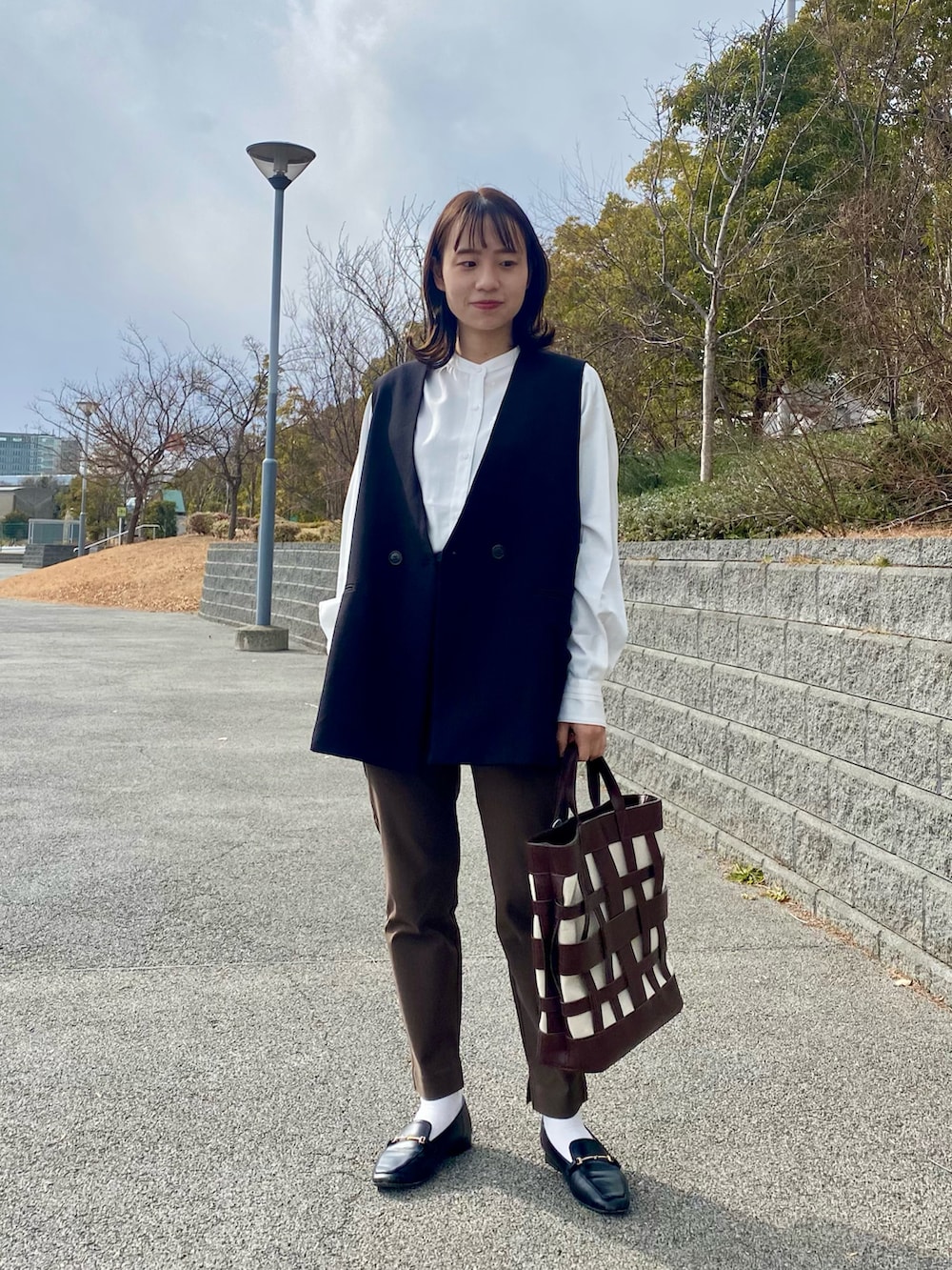 ホワイト系のシャツ/ブラウス、ブラック系のベスト、ブラウン系のその他パンツを着用したレディースの冬コーディネートの2枚目の写真