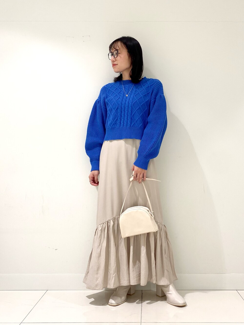 ブルー系のワンピース、ホワイト系のショルダーバッグ、ホワイト系のブーツを着用したレディースの冬コーディネートの2枚目の写真