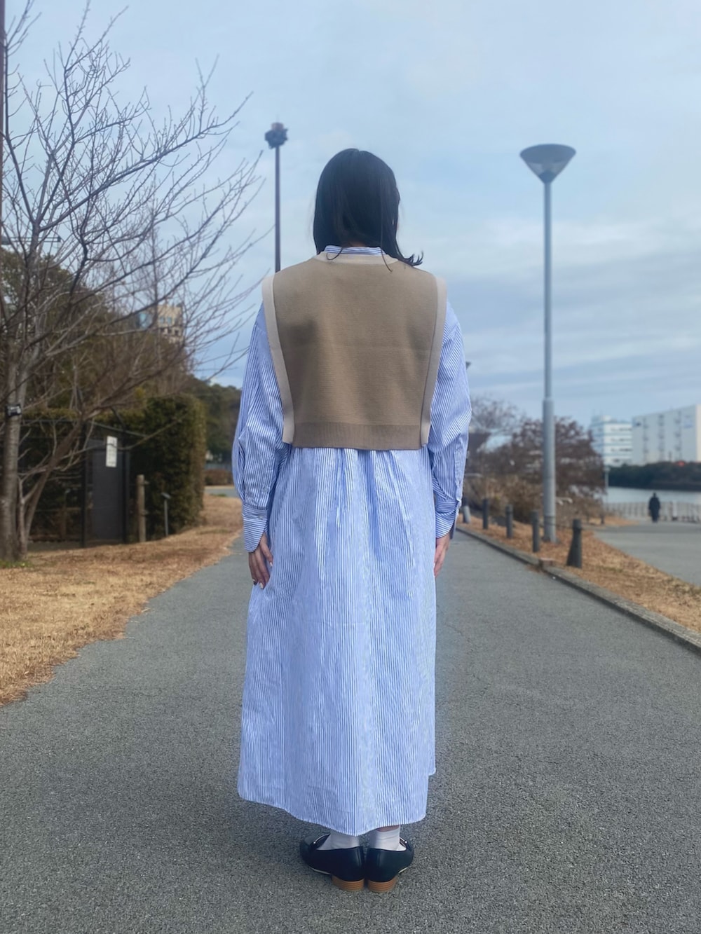 ベージュ系のベスト、ブルー系のシャツワンピース、ブラック系のローファーを着用したレディースの冬コーディネートの3枚目の写真