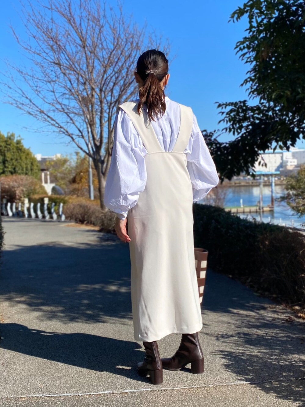 ホワイト系のジャンパースカート、ブラウン系のブーツ、ホワイト系のシャツ/ブラウスを着用したレディースの冬コーディネートの4枚目の写真