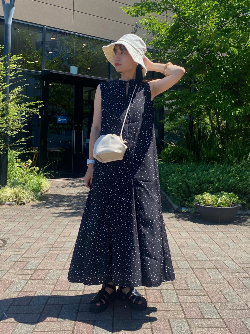 ブラック系のワンピース、ブラック系のサンダル、ホワイト系のショルダーバッグを着用したレディースの夏コーディネートの2枚目の写真