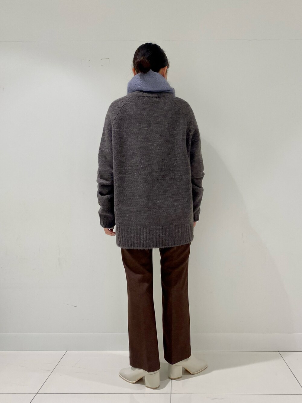 グレー系のニット/セーター、ホワイト系のTシャツ/カットソー、ホワイト系のブーツを着用したレディースの冬コーディネートの3枚目の写真
