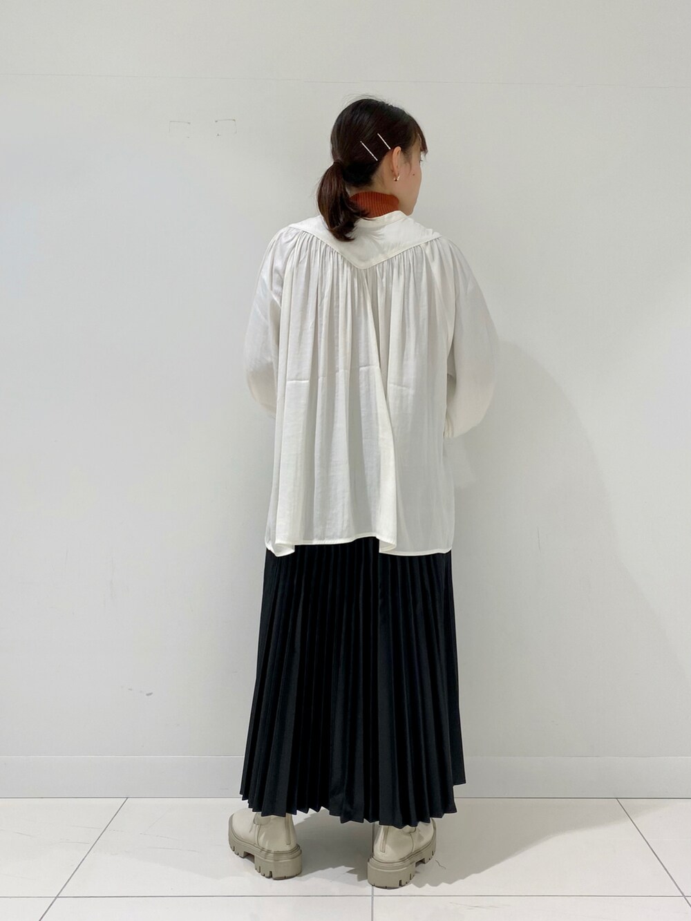 ホワイト系のシャツ/ブラウス、オレンジ系のニット/セーター、ブラック系のスカートを着用したレディースの秋コーディネートの2枚目の写真