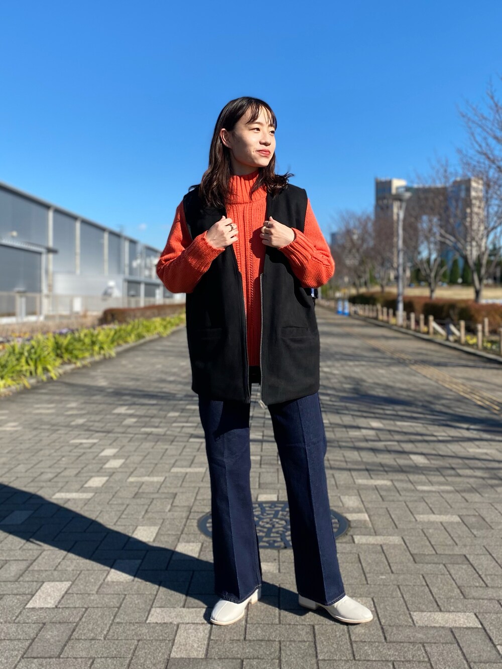 ピンク系のニット/セーター、ブラック系のベスト、ホワイト系のその他シューズを着用したレディースの冬コーディネートの2枚目の写真