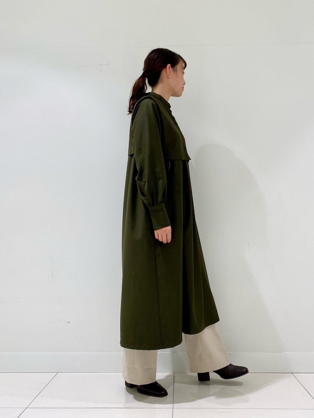 グリーン系のワンピース、ブラウン系のブーツ、ホワイト系のその他パンツを着用したレディースの冬コーディネートの2枚目の写真