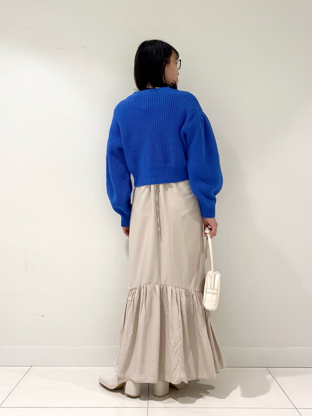 ブルー系のワンピース、ホワイト系のショルダーバッグ、ホワイト系のブーツを着用したレディースの冬コーディネートの3枚目の写真