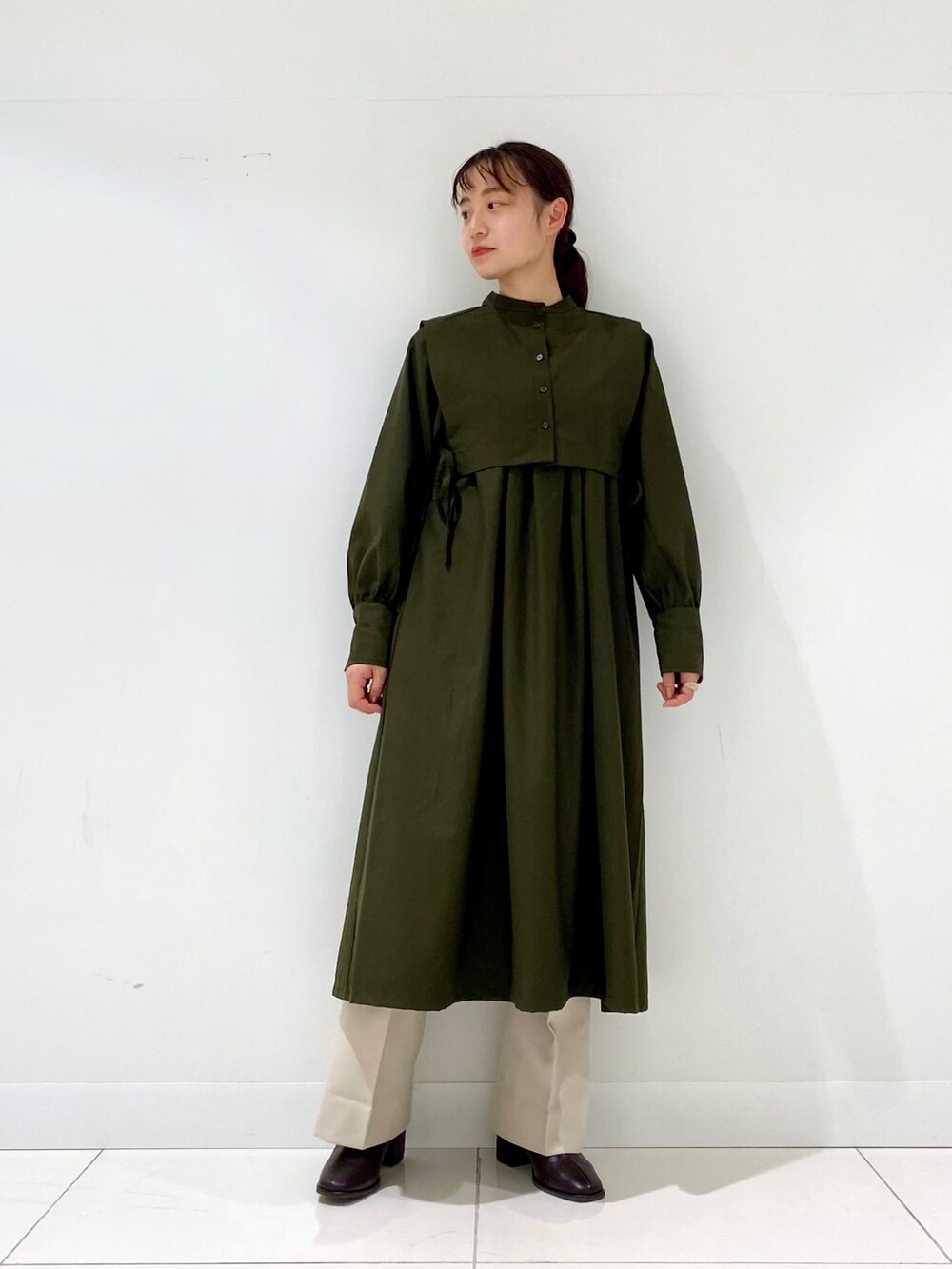 グリーン系のワンピース、ブラウン系のブーツ、ホワイト系のその他パンツを着用したレディースの冬コーディネートの4枚目の写真