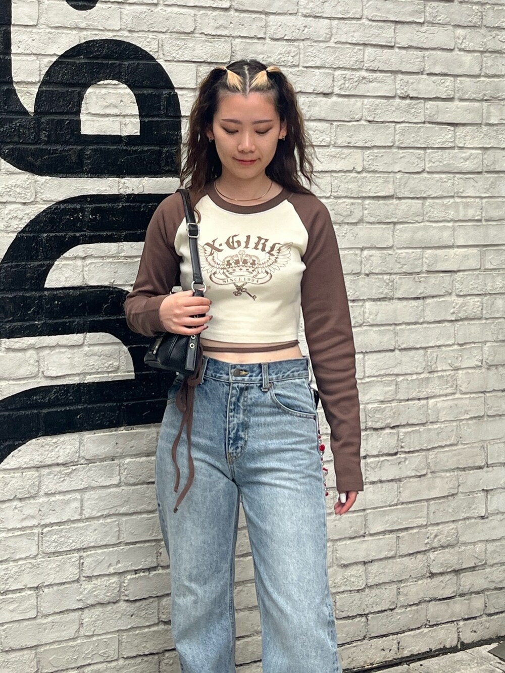 ホワイト系のTシャツ/カットソー、ブラック系のショルダーバッグ、ブルー系のデニムパンツを着用したレディースの夏コーディネートの3枚目の写真