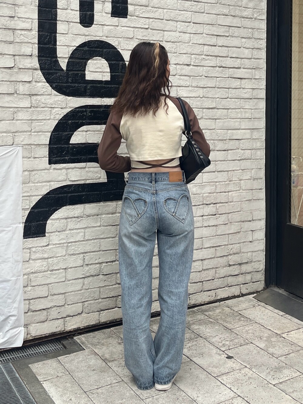 ホワイト系のTシャツ/カットソー、ブラック系のショルダーバッグ、ブルー系のデニムパンツを着用したレディースの夏コーディネートの2枚目の写真