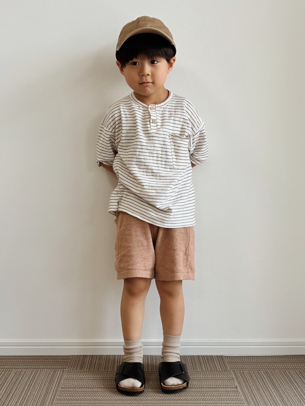 ホワイト系のTシャツ/カットソー、ブラウン系のパンツ、ブラック系のサンダルを着用したキッズの夏コーディネートの2枚目の写真