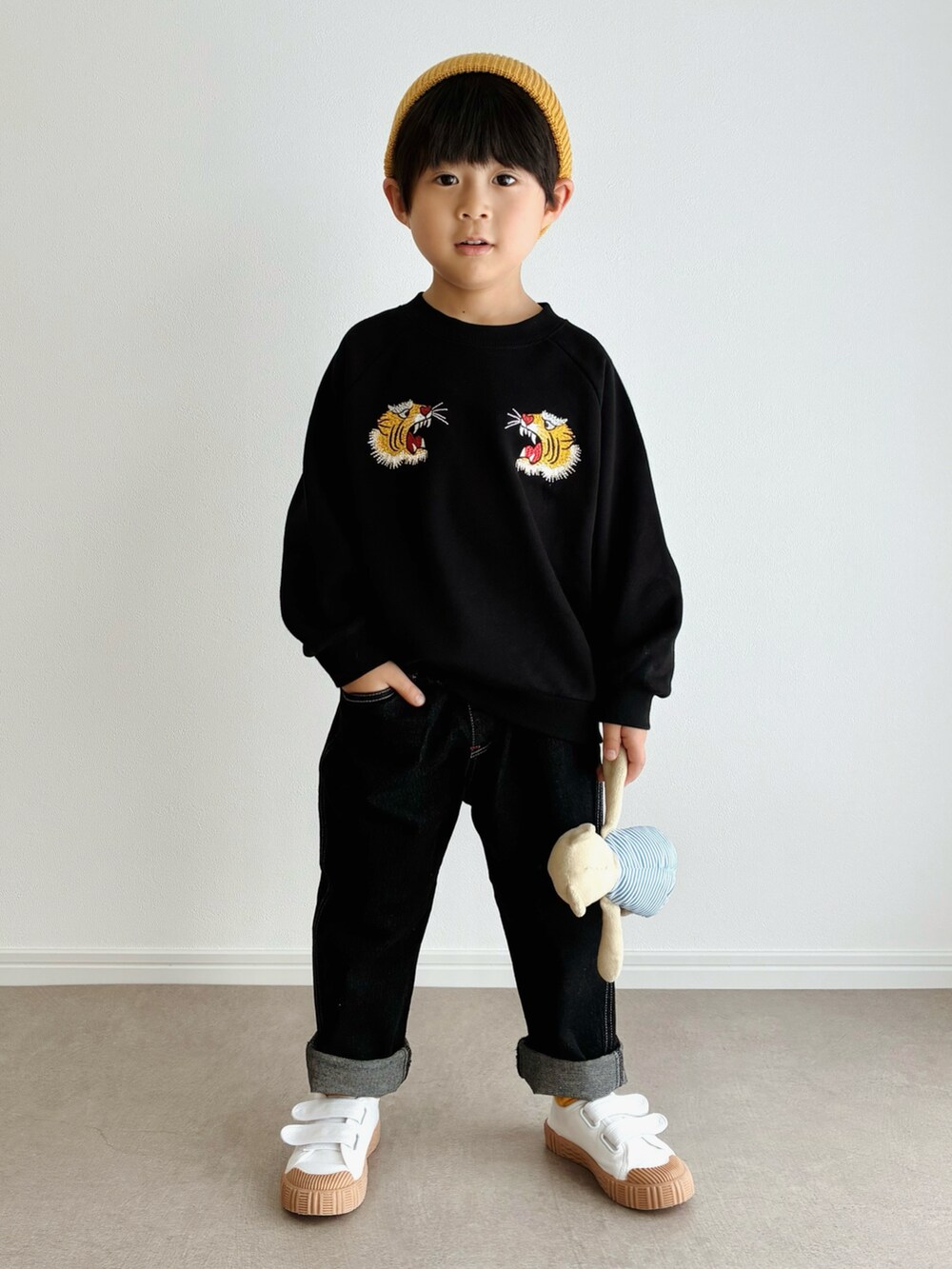 ベージュ系のスリッポン、ブラック系のスウェット、ブラック系のデニムパンツを着用したキッズの秋コーディネートの2枚目の写真