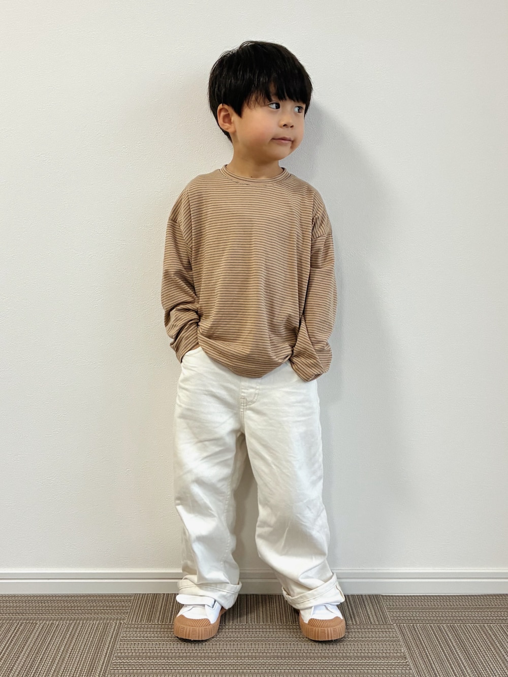 ベージュ系のスリッポン、ブラウン系のTシャツ/カットソー、ホワイト系のパンツを着用したキッズの秋コーディネートの2枚目の写真