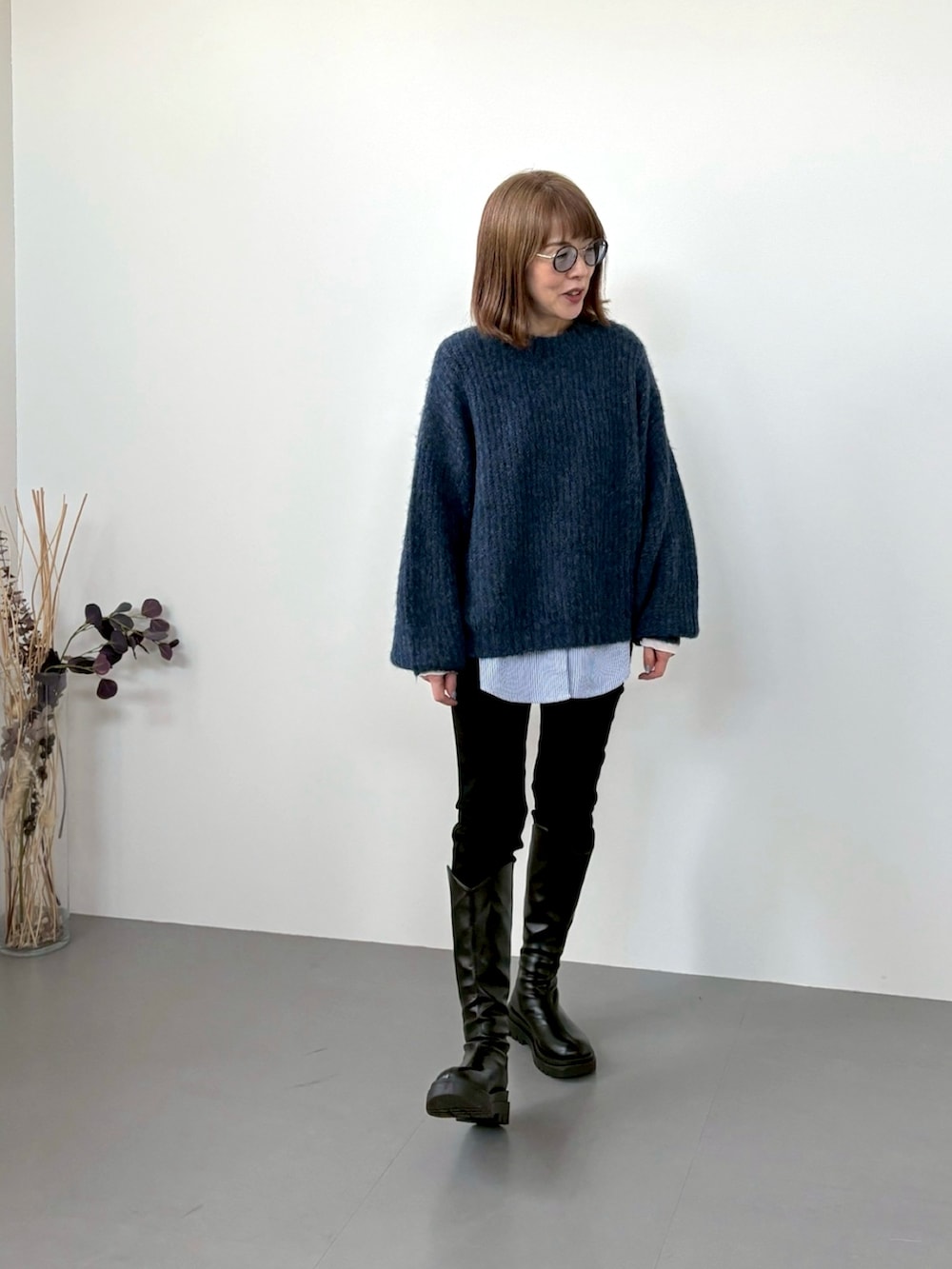 ブルー系のニット/セーター、ホワイト系のTシャツ/カットソー、ブラック系のデニムパンツを着用したレディースの冬コーディネートの2枚目の写真