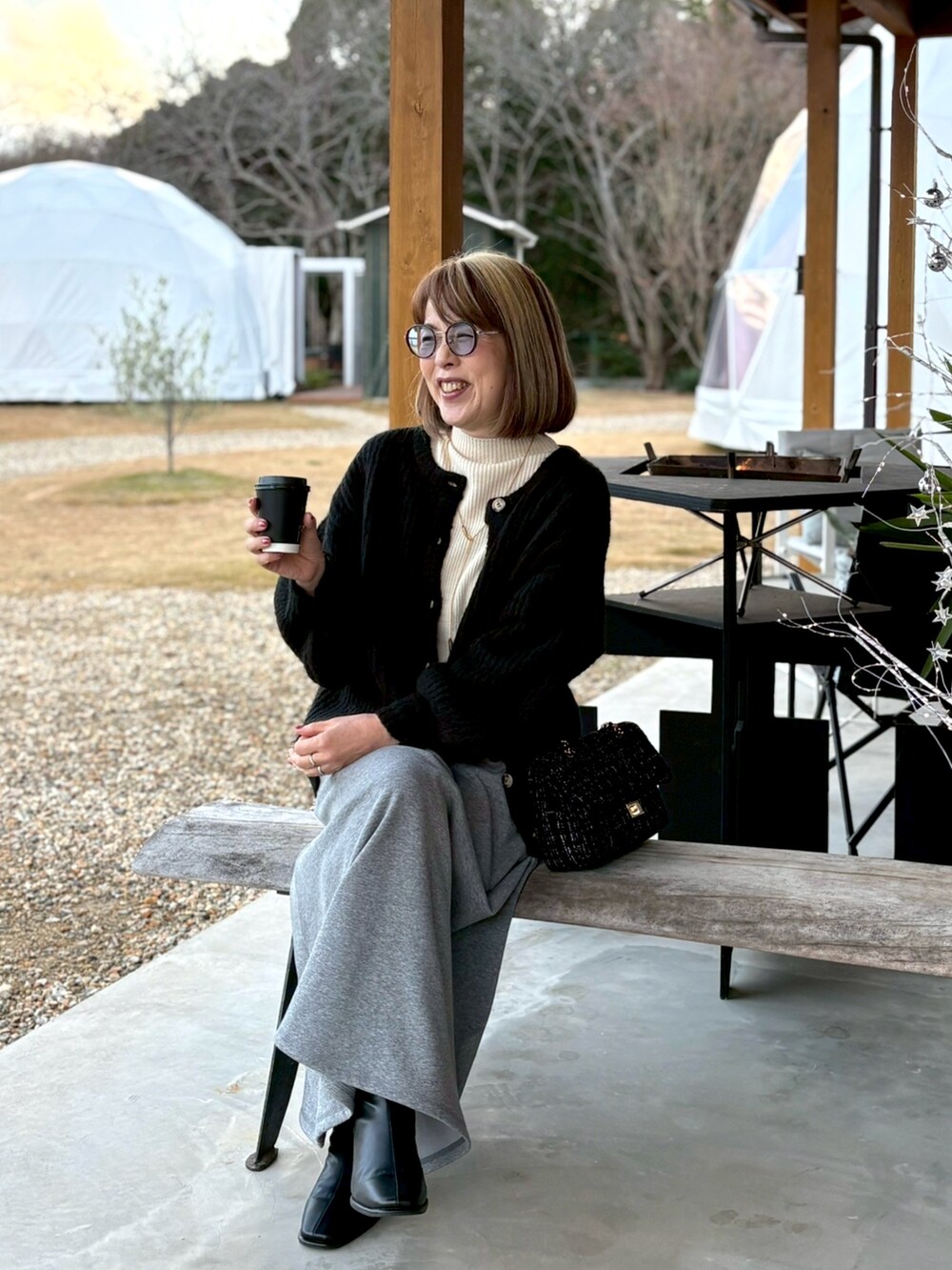 ホワイト系のニット/セーター、ブラック系のカーディガン/ボレロ、グレー系のスカートを着用したレディースの冬コーディネートの3枚目の写真