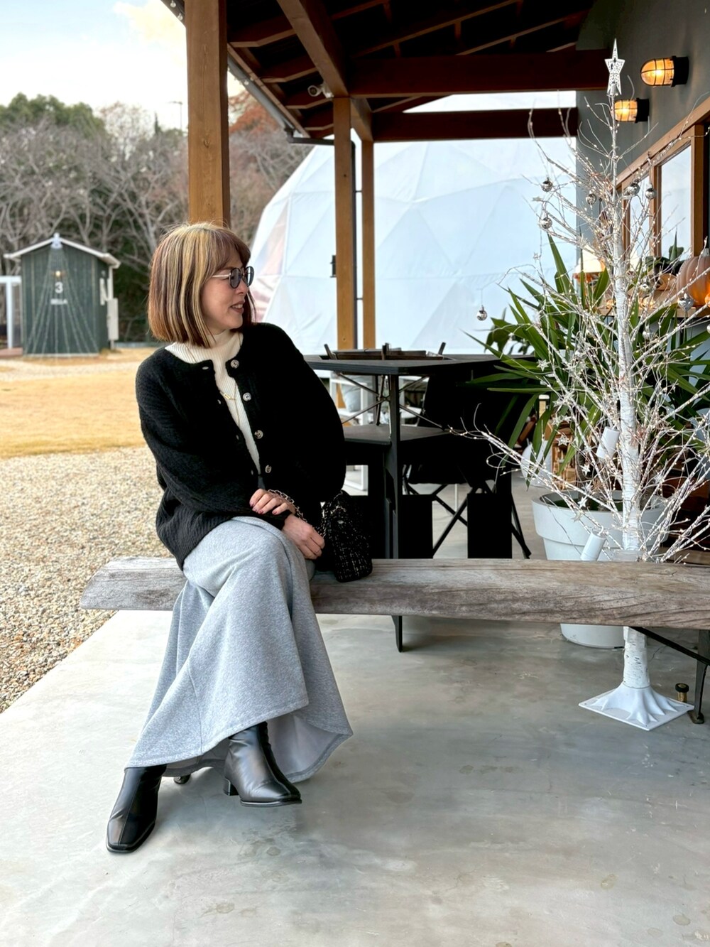 ホワイト系のニット/セーター、ブラック系のカーディガン/ボレロ、グレー系のスカートを着用したレディースの冬コーディネートの4枚目の写真