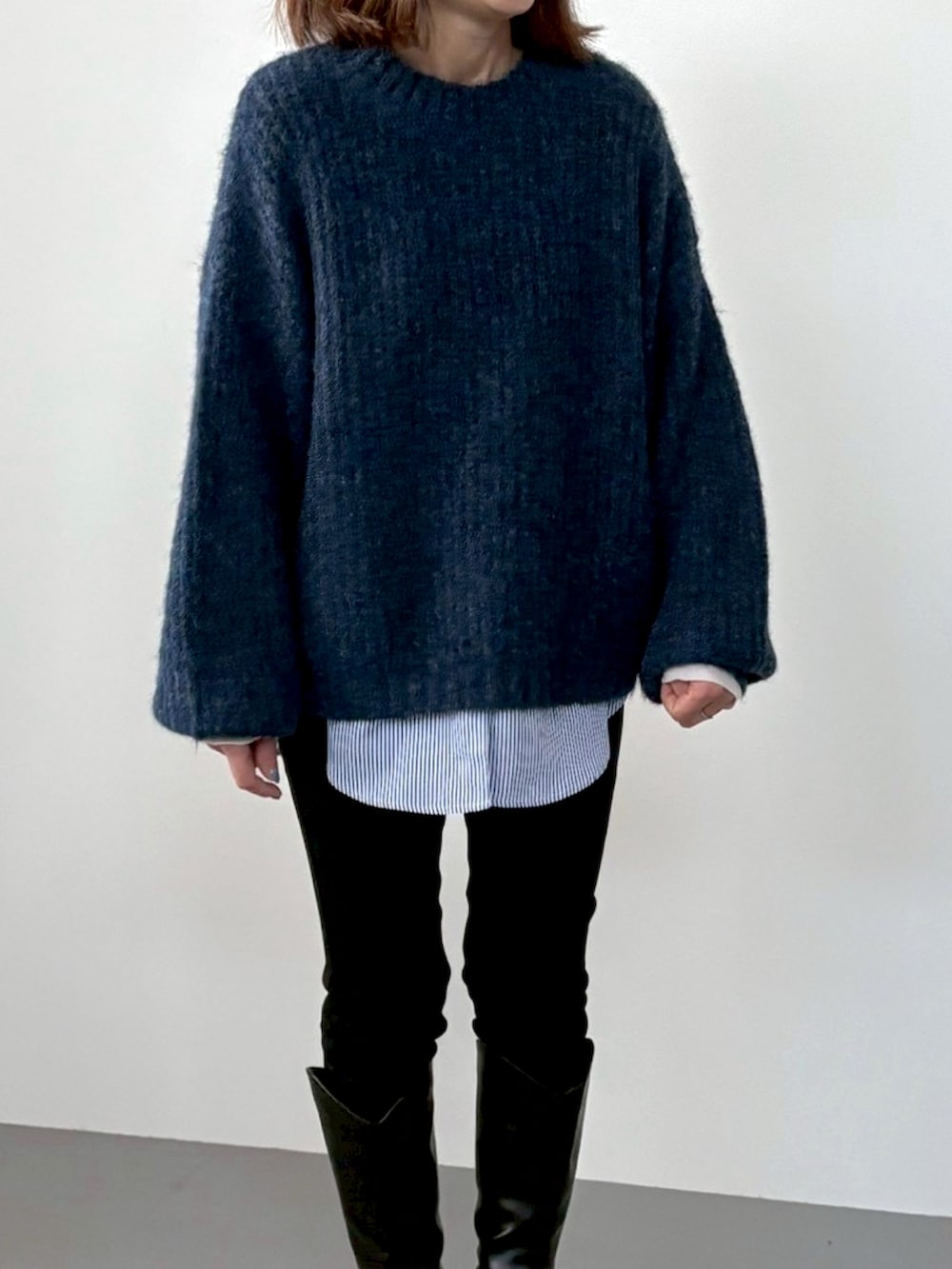 ブルー系のニット/セーター、ホワイト系のTシャツ/カットソー、ブラック系のデニムパンツを着用したレディースの冬コーディネートの3枚目の写真