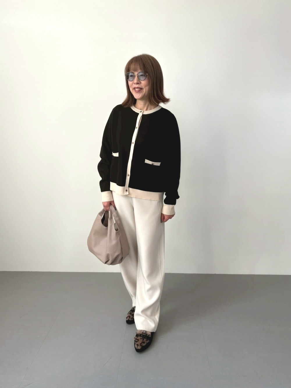 ベージュ系のカーディガン/ボレロ、ホワイト系のパンツ、ベージュ系のバッグを着用したレディースの冬コーディネートの2枚目の写真