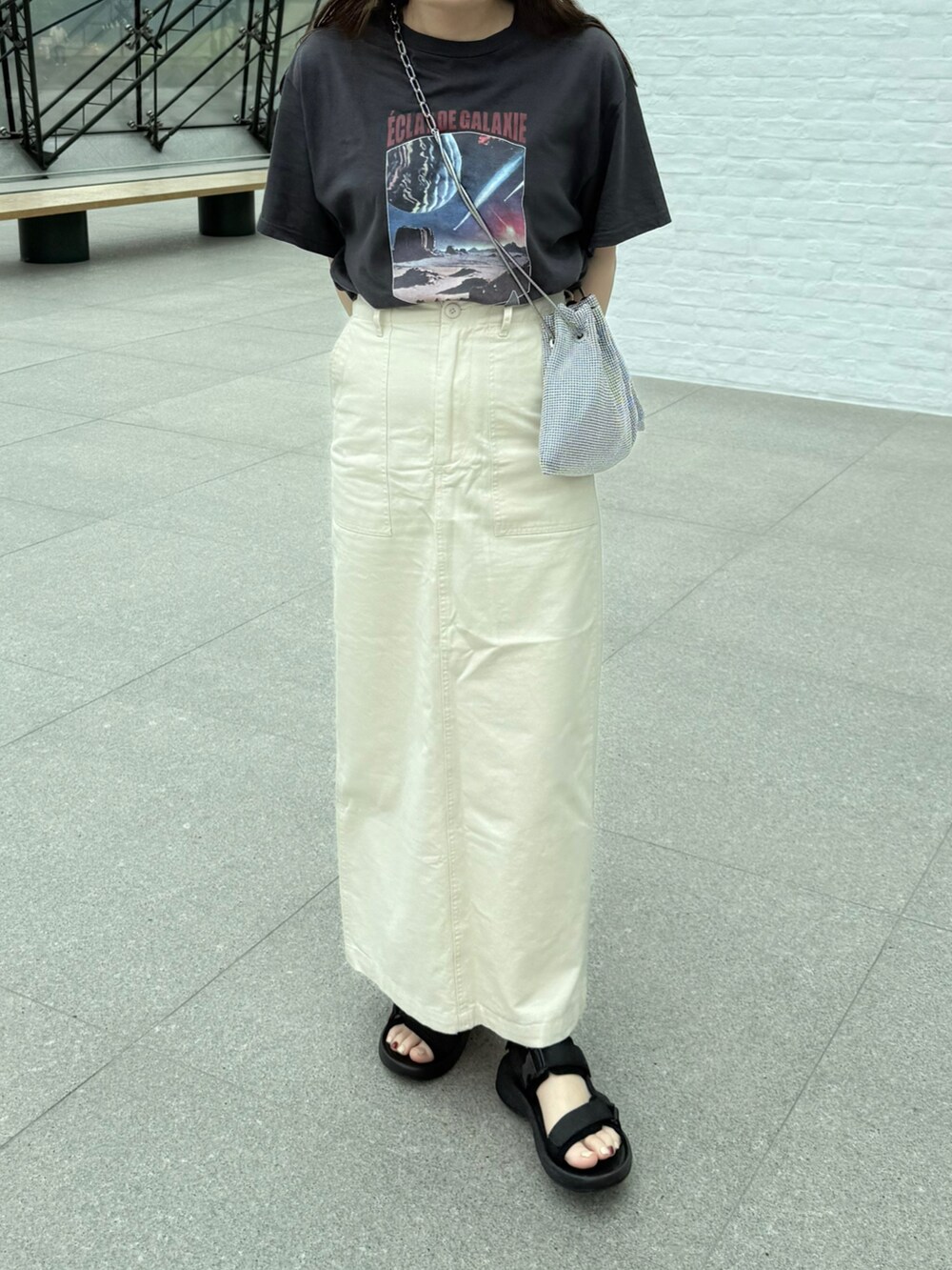 グレー系のTシャツ/カットソー、シルバー系のショルダーバッグ、ホワイト系のスカートを着用したレディースの夏コーディネートの2枚目の写真