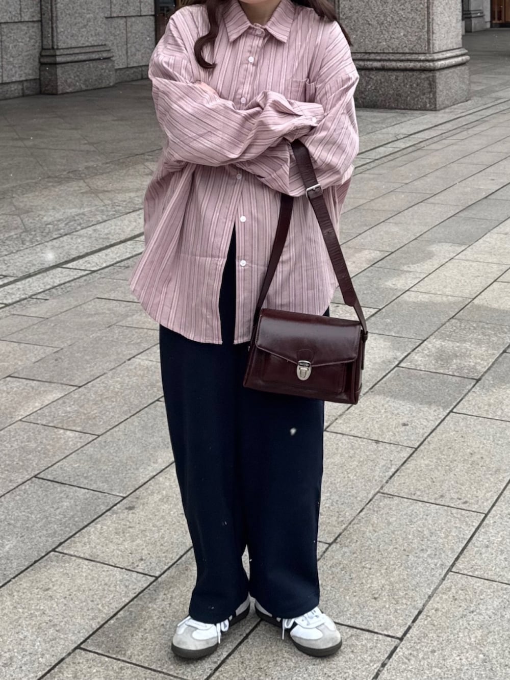 ブラウン系のバッグ、ブルー系のパンツ、ホワイト系のスニーカーを着用したレディースの春コーディネートの2枚目の写真