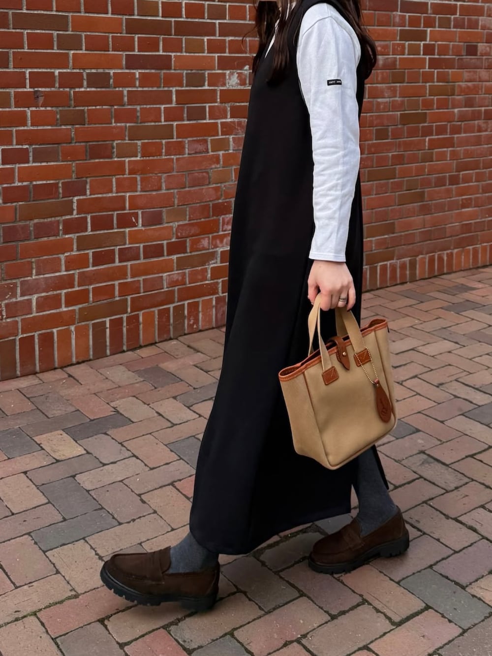 ホワイト系のTシャツ/カットソー、ブラック系のワンピース、ベージュ系のバッグを着用したレディースの冬コーディネートの2枚目の写真