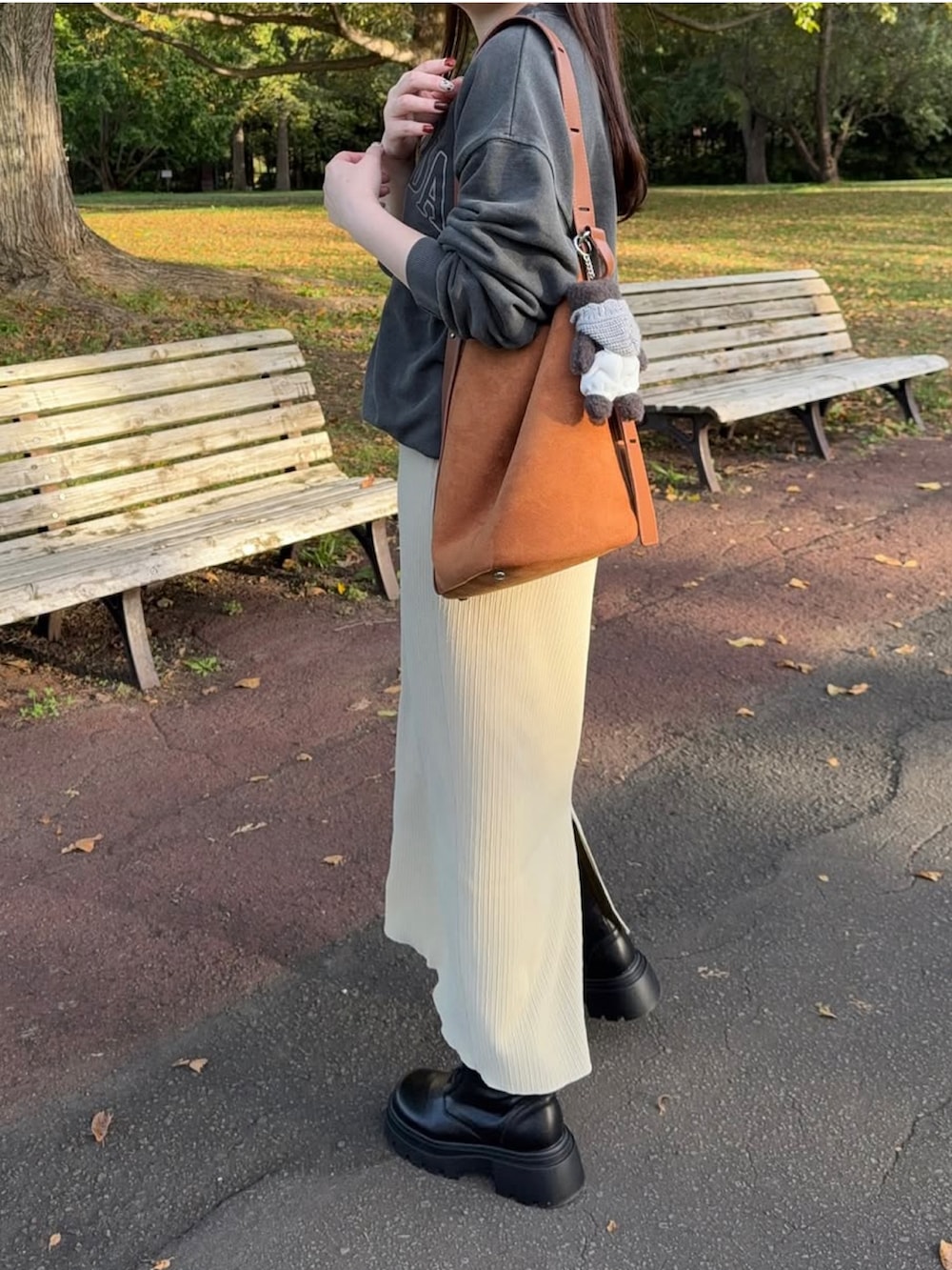 ベージュ系のスカート、ブラック系のブーツを着用したレディースの秋コーディネートの2枚目の写真