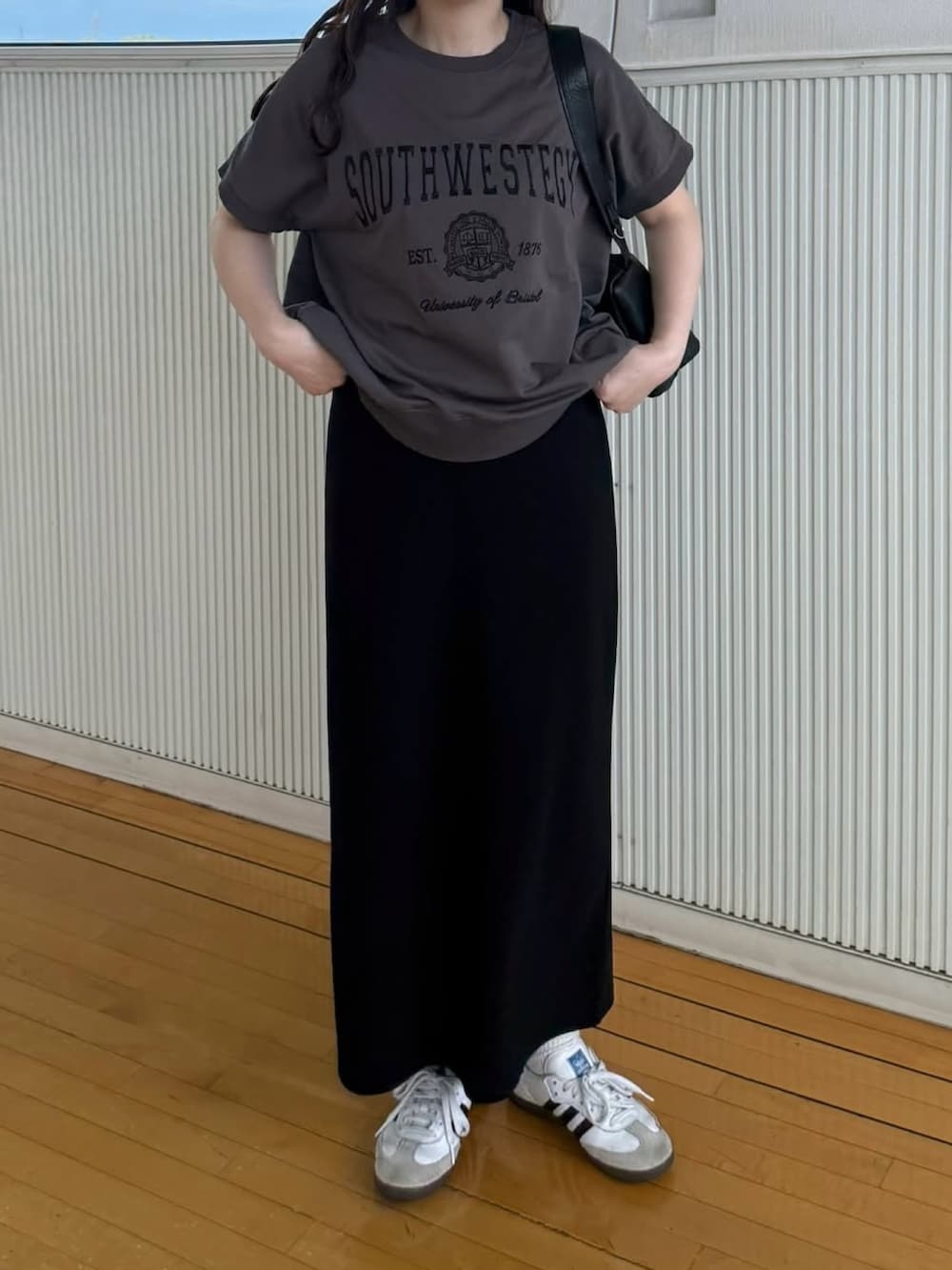 グレー系のTシャツ/カットソー、ブラック系のショルダーバッグ、ホワイト系のスニーカーを着用したレディースの秋コーディネートの2枚目の写真