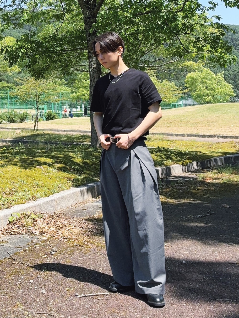 ブラック系のTシャツ/カットソー、グレー系のスラックス、ブラック系のドレスシューズを着用したメンズの春コーディネートの2枚目の写真