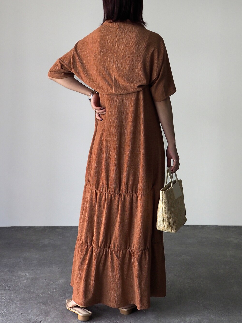 オレンジ系のワンピース、ホワイト系のショルダーバッグを着用したレディースの春コーディネートの3枚目の写真