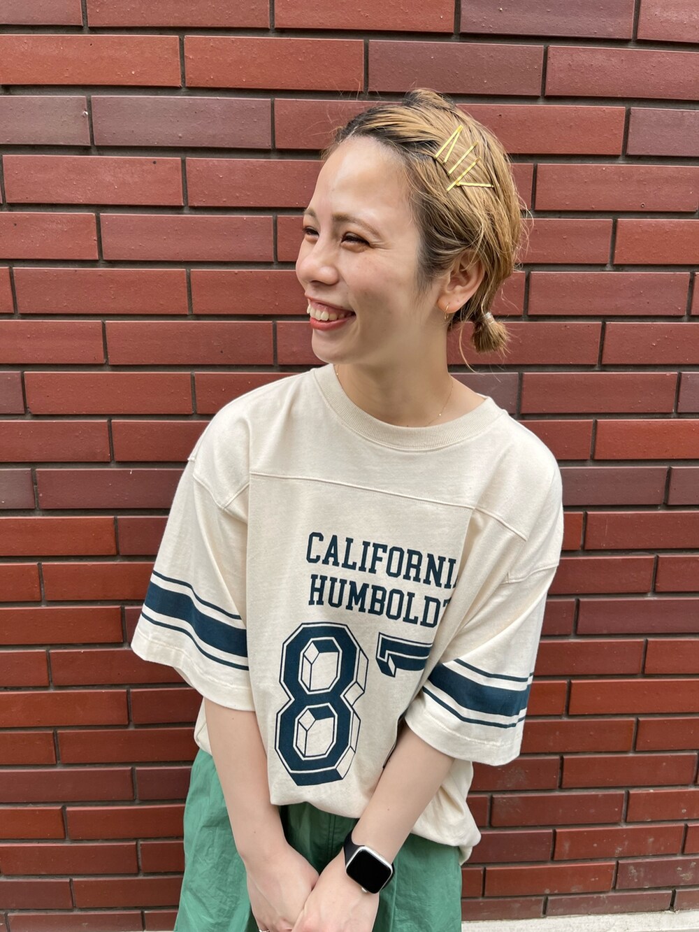 ベージュ系のTシャツ/カットソー、オレンジ系のエコバッグ/サブバッグ、ブラック系のサンダルを着用したレディースの夏コーディネートの3枚目の写真