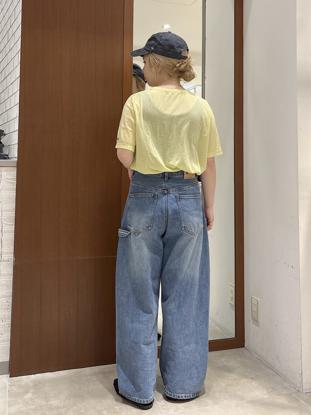 ブルー系のデニムパンツ、イエロー系のTシャツ/カットソー、ブラック系のサンダルを着用したレディースの春コーディネートの2枚目の写真