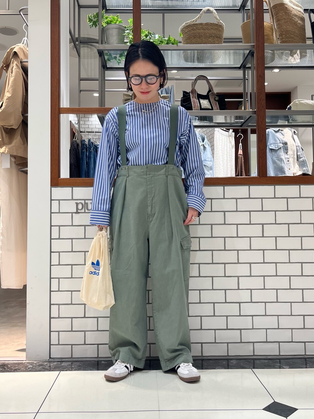 グリーン系のパンツ、ホワイト系のカーディガン/ボレロ、ブルー系のシャツ/ブラウスを着用したレディースの春コーディネートの2枚目の写真