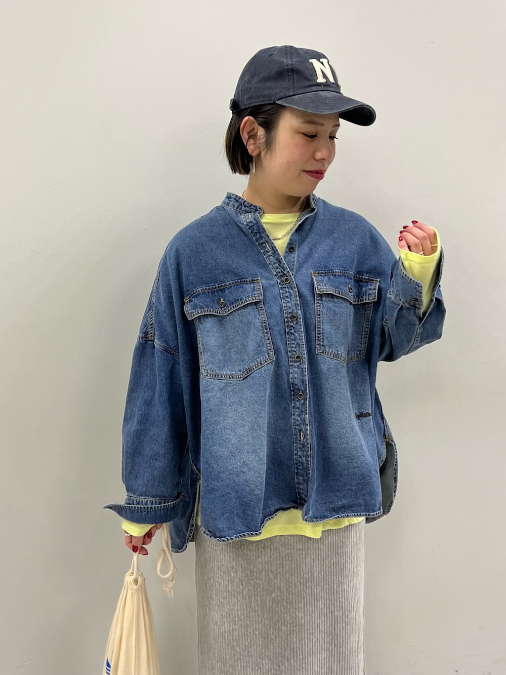 グレー系のスカート、ブルー系のシャツ/ブラウス、イエロー系のTシャツ/カットソーを着用したレディースの冬コーディネートの2枚目の写真