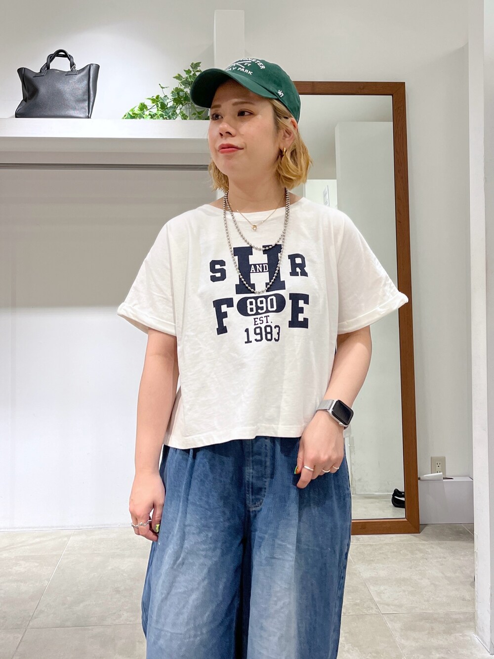 ブルー系のデニムパンツ、ブラック系のハンドバッグ、ホワイト系のTシャツ/カットソーを着用したレディースの春コーディネートの2枚目の写真