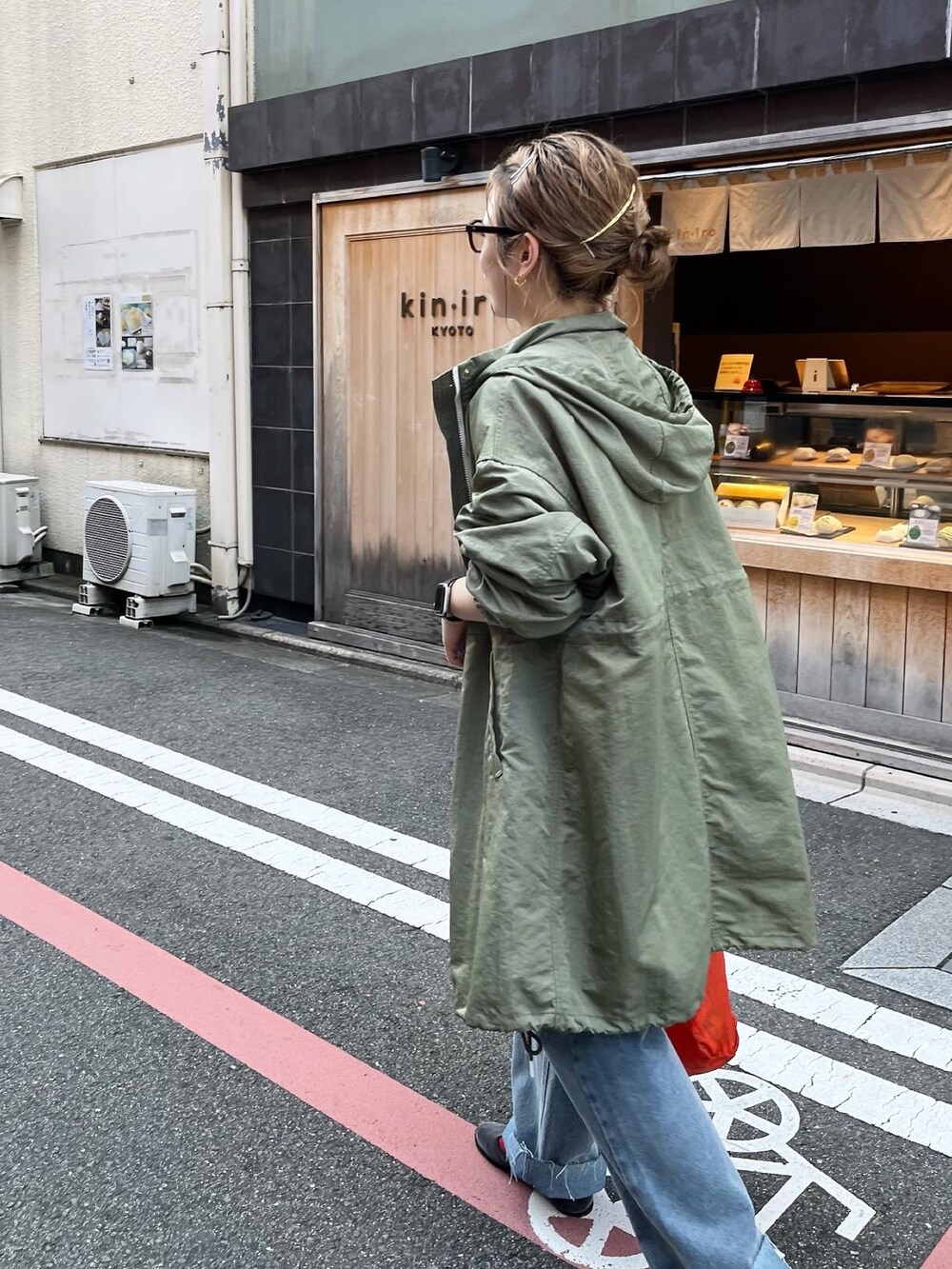 グリーン系のモッズコート、ブラック系のTシャツ/カットソー、ブルー系のデニムパンツを着用したレディースの秋コーディネートの3枚目の写真