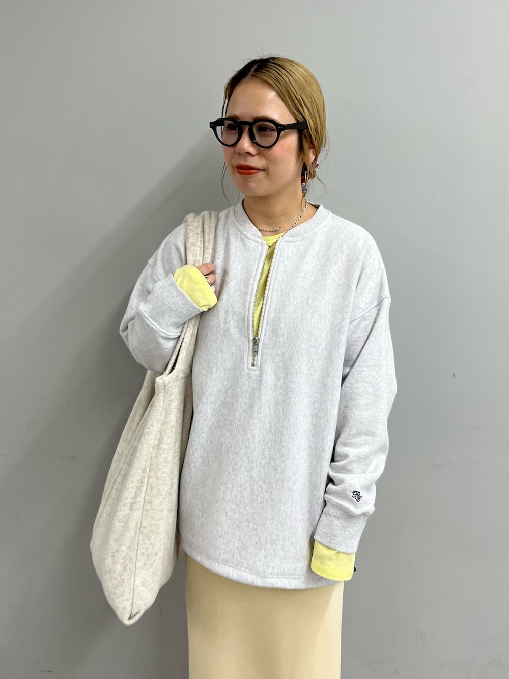 グレー系のスウェット、イエロー系のTシャツ/カットソー、ホワイト系のスカートを着用したレディースの冬コーディネートの2枚目の写真