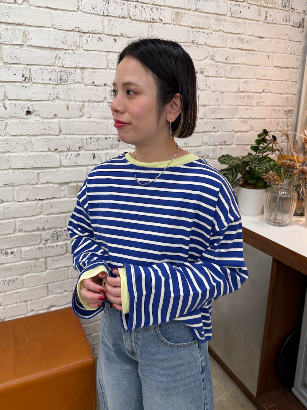 ブルー系のデニムパンツ、イエロー系のTシャツ/カットソー、イエロー系のスニーカーを着用したレディースの冬コーディネートの2枚目の写真