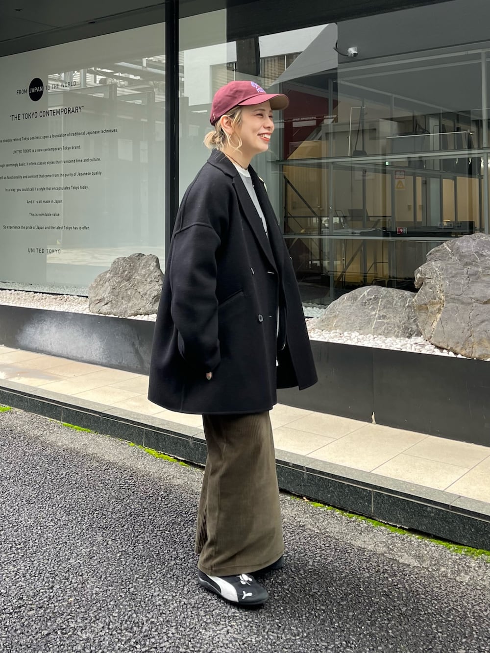 グリーン系のスカート、ホワイト系のTシャツ/カットソー、ブラック系のTシャツ/カットソーを着用したレディースの秋コーディネートの2枚目の写真