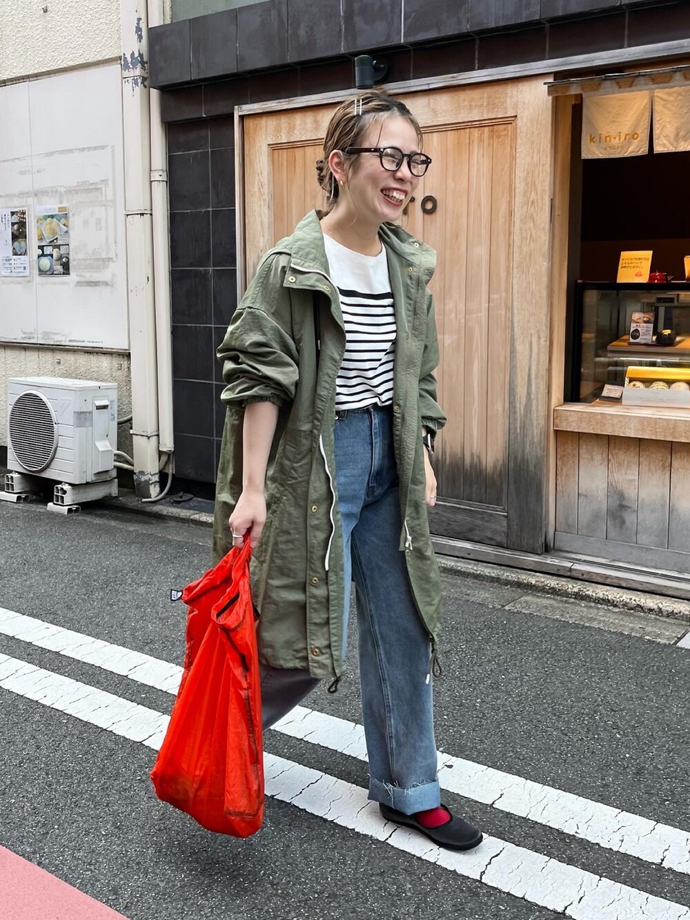 グリーン系のモッズコート、ブラック系のTシャツ/カットソー、ブルー系のデニムパンツを着用したレディースの秋コーディネートの2枚目の写真