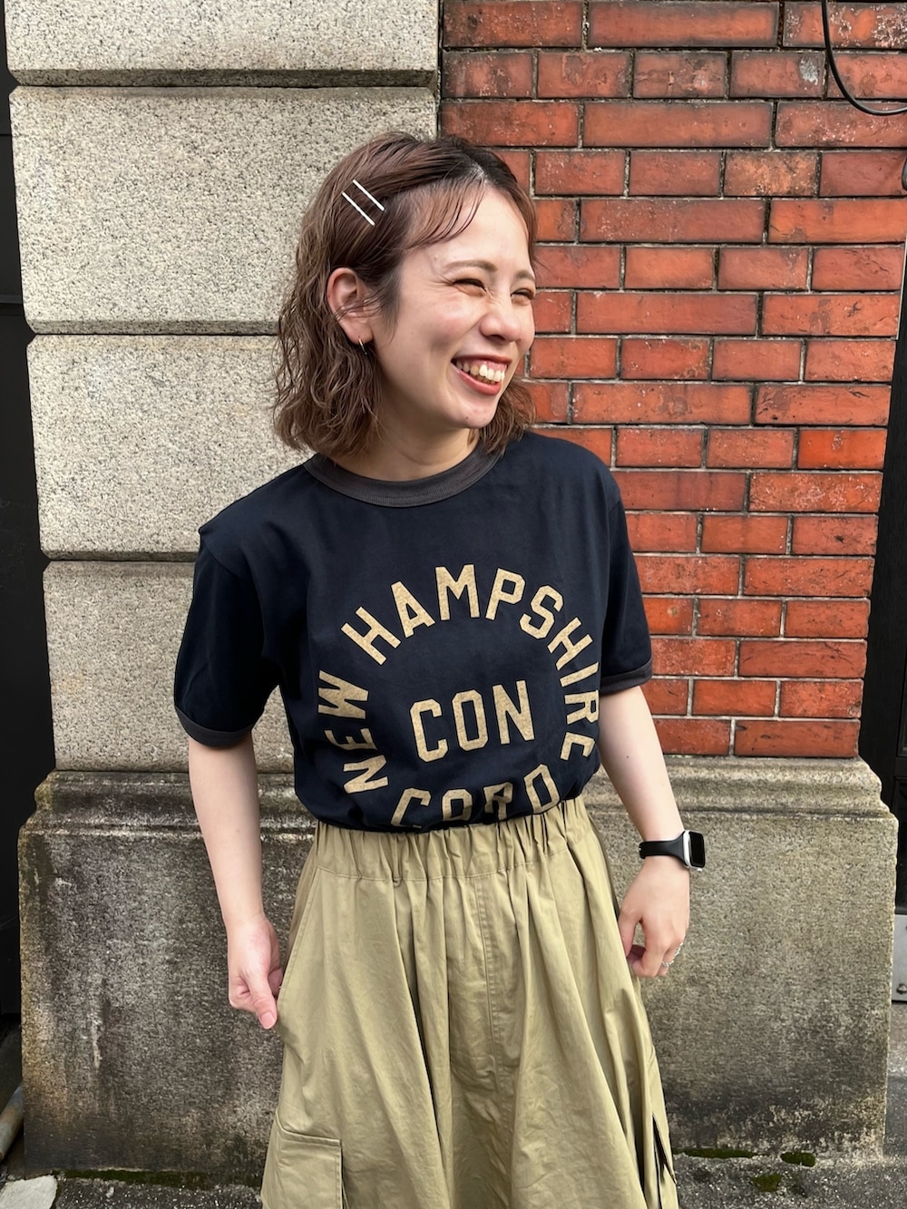 グリーン系のスカート、ブルー系のTシャツ/カットソー、ブラック系のサンダルを着用したレディースの夏コーディネートの2枚目の写真