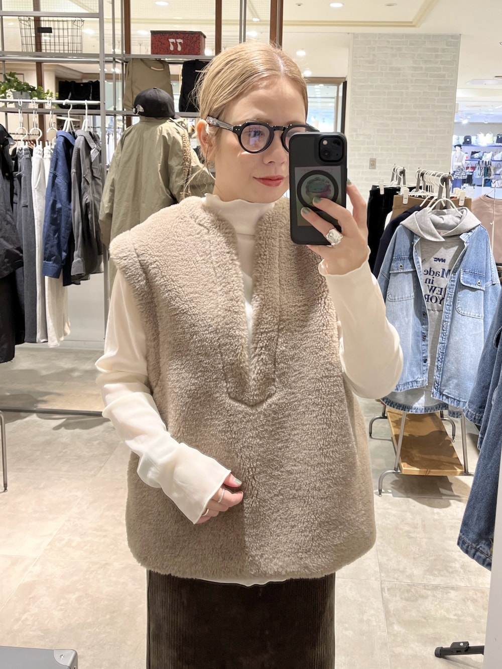 ベージュ系のベスト、グリーン系のスカート、ホワイト系のTシャツ/カットソーを着用したレディースの秋コーディネートの2枚目の写真