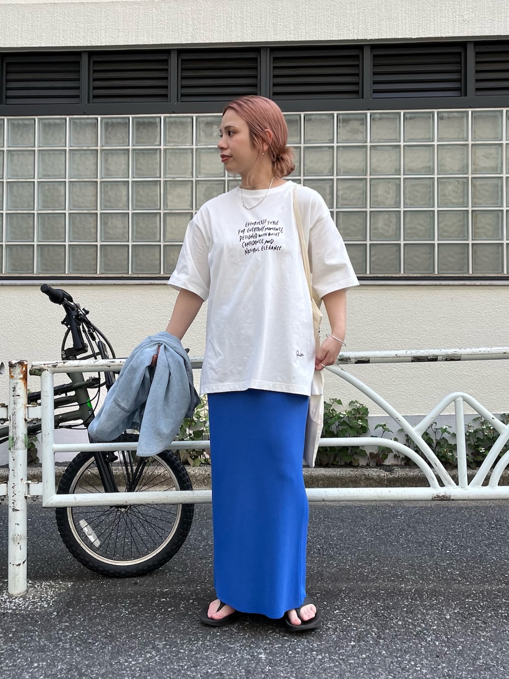 ブルー系のスカート、ブラック系のサンダル、ホワイト系のTシャツ/カットソーを着用したレディースの夏コーディネートの2枚目の写真