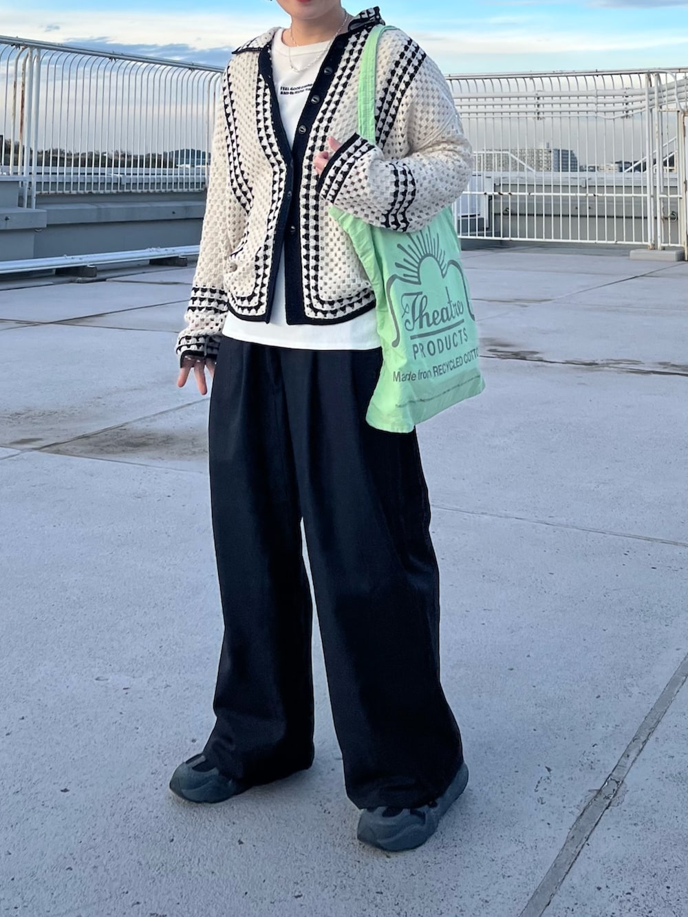 グリーン系のトートバッグ、ホワイト系のカーディガン/ボレロ、ホワイト系のTシャツ/カットソーを着用したレディースの冬コーディネートの2枚目の写真