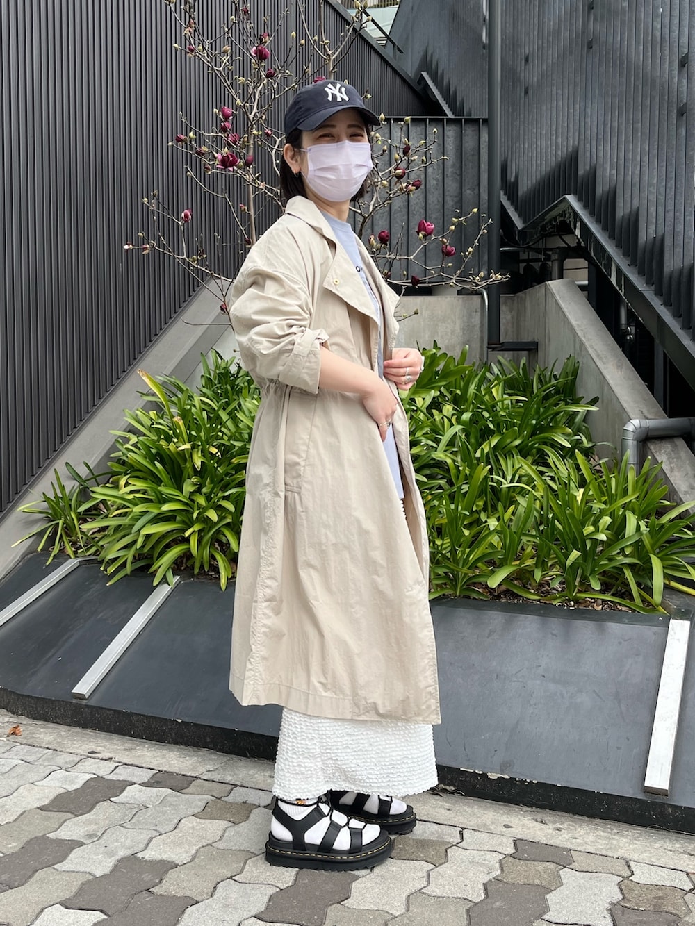 グレー系のTシャツ/カットソー、ベージュ系のチェスターコート、ホワイト系のスカートを着用したレディースの春コーディネートの2枚目の写真