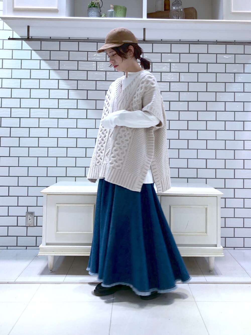 ホワイト系のニット/セーター、ホワイト系のTシャツ/カットソー、ブルー系のスカートを着用したレディースの冬コーディネートの2枚目の写真