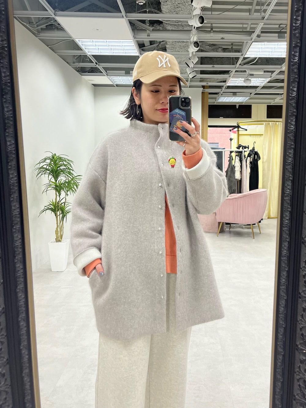 ベージュ系のスウェットパンツ、オレンジ系のスウェット、ベージュ系のノーカラーコートを着用したレディースの秋コーディネートの2枚目の写真