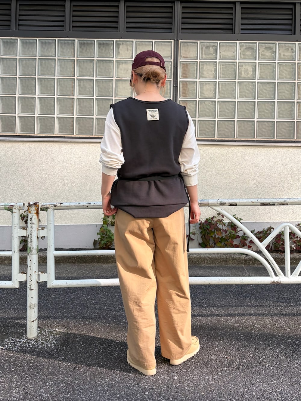 グレー系のベスト、ホワイト系のTシャツ/カットソー、イエロー系のスラックスを着用したレディースの秋コーディネートの2枚目の写真