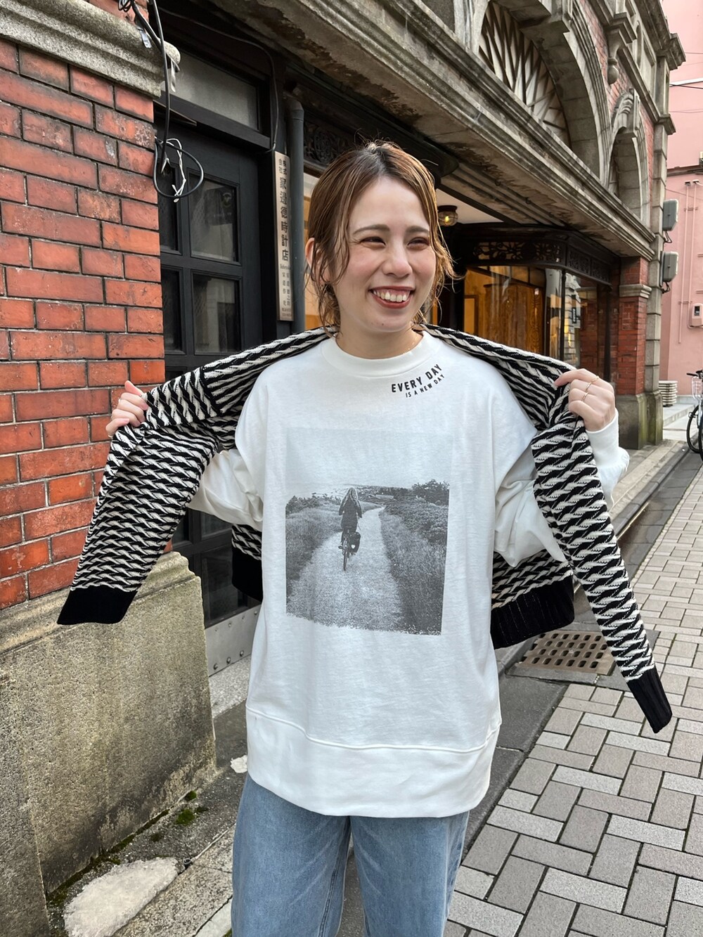 ホワイト系のTシャツ/カットソー、その他のカーディガン/ボレロ、ブルー系のデニムパンツを着用したレディースの秋コーディネートの2枚目の写真