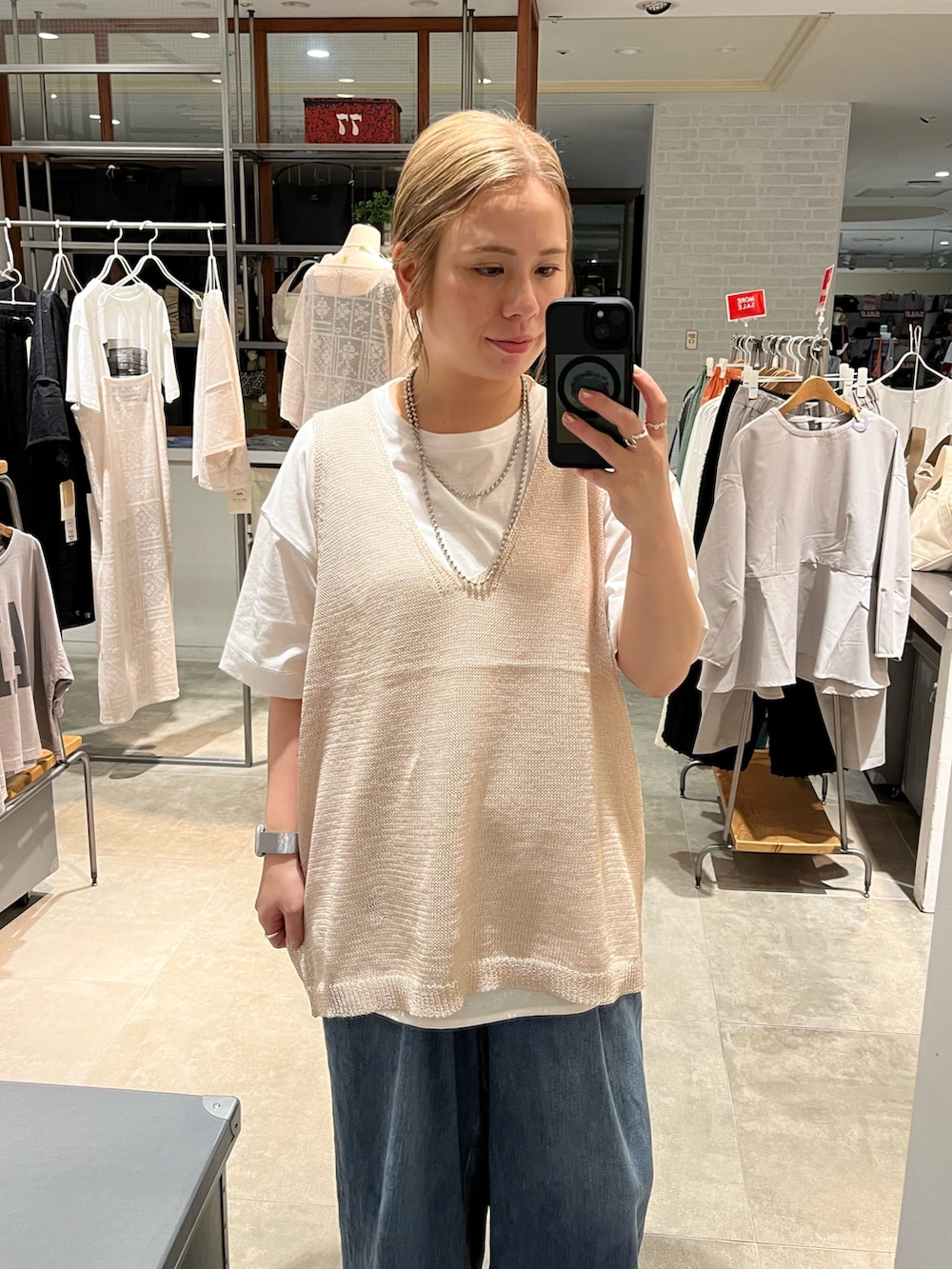 ベージュ系のベスト、ホワイト系のTシャツ/カットソー、ブルー系のデニムパンツを着用したレディースの夏コーディネートの2枚目の写真