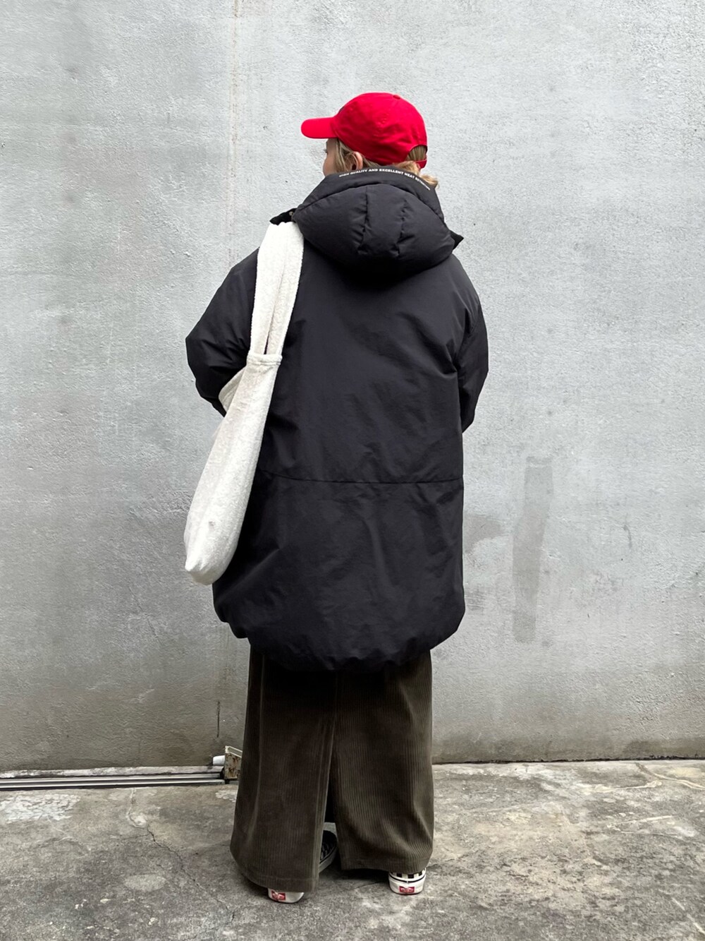 ブラック系のダウンジャケット/コート、ホワイト系のTシャツ/カットソー、ベージュ系のバッグを着用したレディースの秋コーディネートの3枚目の写真