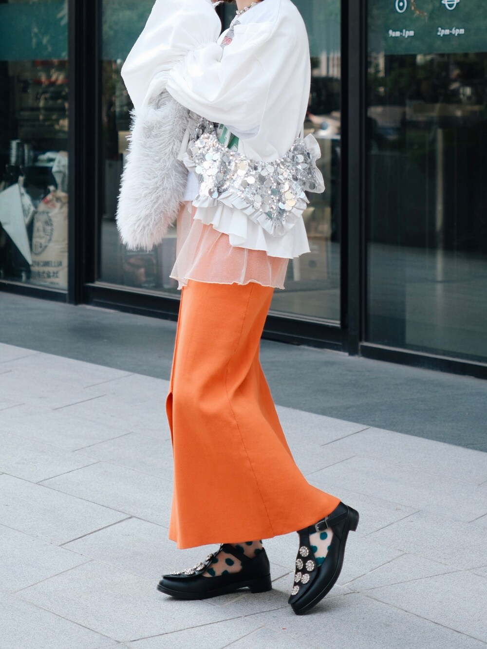 オレンジ系のスカート、ホワイト系のハンドバッグ、ホワイト系のTシャツ/カットソーを着用したレディースの冬コーディネートの2枚目の写真